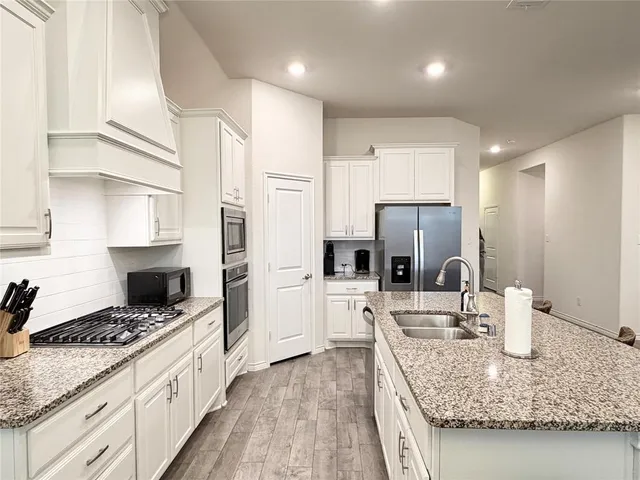 a kitchen with stainless steel appliances kitchen island granite countertop a stove refrigerator and cabinets