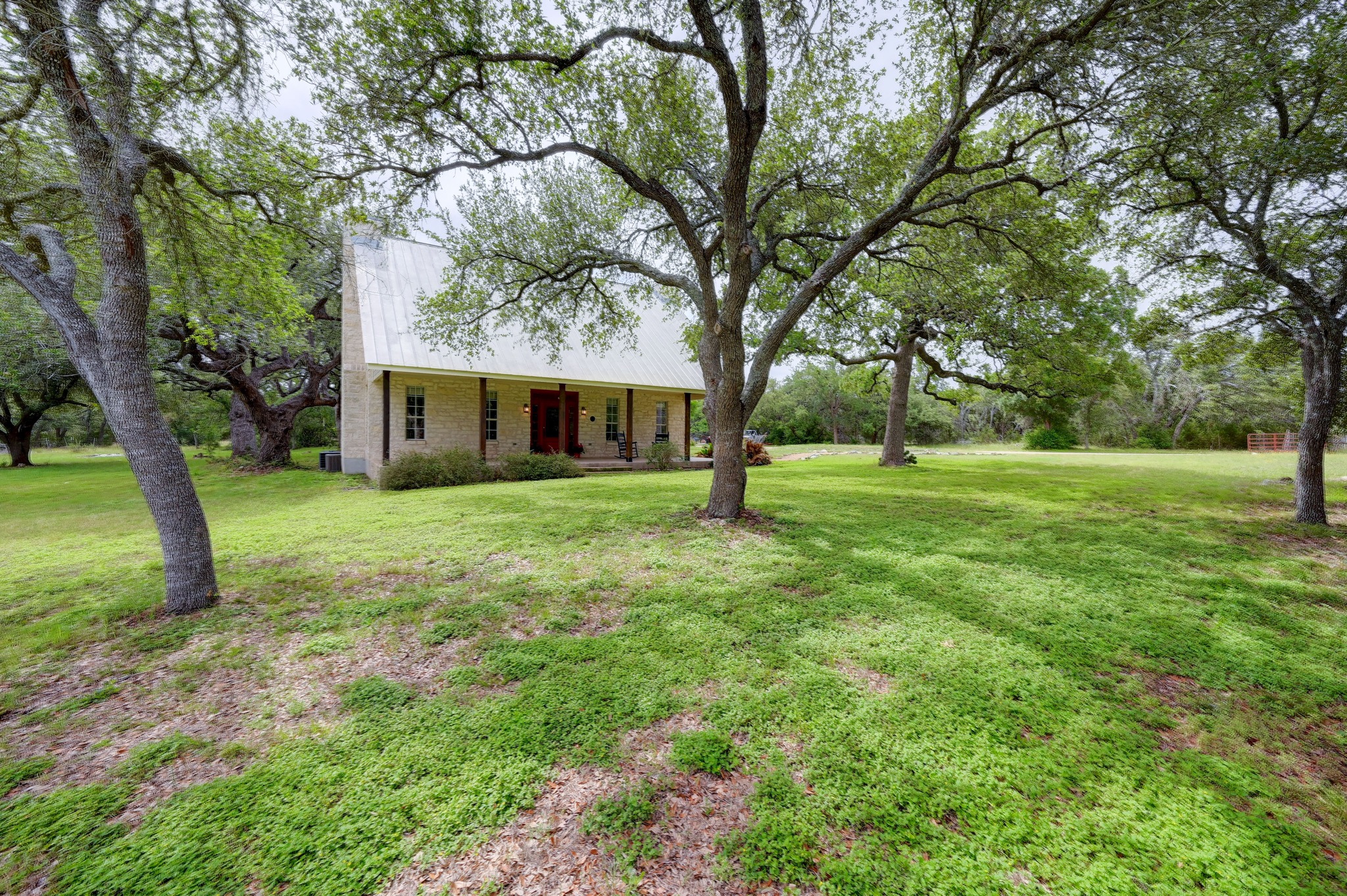364 Nameless Road Driftwood, TX 78619 - Photo 2 of 32 A charming country residence nestled under mature shade trees, offering peaceful outdoor living.