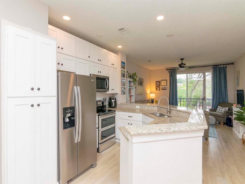 1036 Normandy Trace Road Tampa, FL 33602 - Photo 6 of 31 a kitchen with stainless steel appliances kitchen island granite countertop a refrigerator a stove and a sink with large window