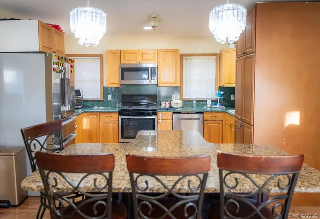 a kitchen with stainless steel appliances kitchen island granite countertop a table chairs in it and wooden floors