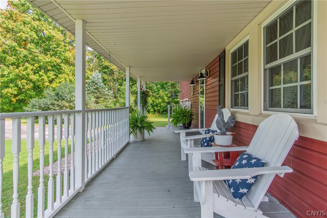 15384 Fuller Road Adams, NY 13606 - Photo 7 of 50 An inviting covered porch features traditional wood decking, classic railings, and peaceful tree-lined views.