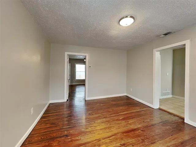 an empty room with wooden floor chandelier fan and windows