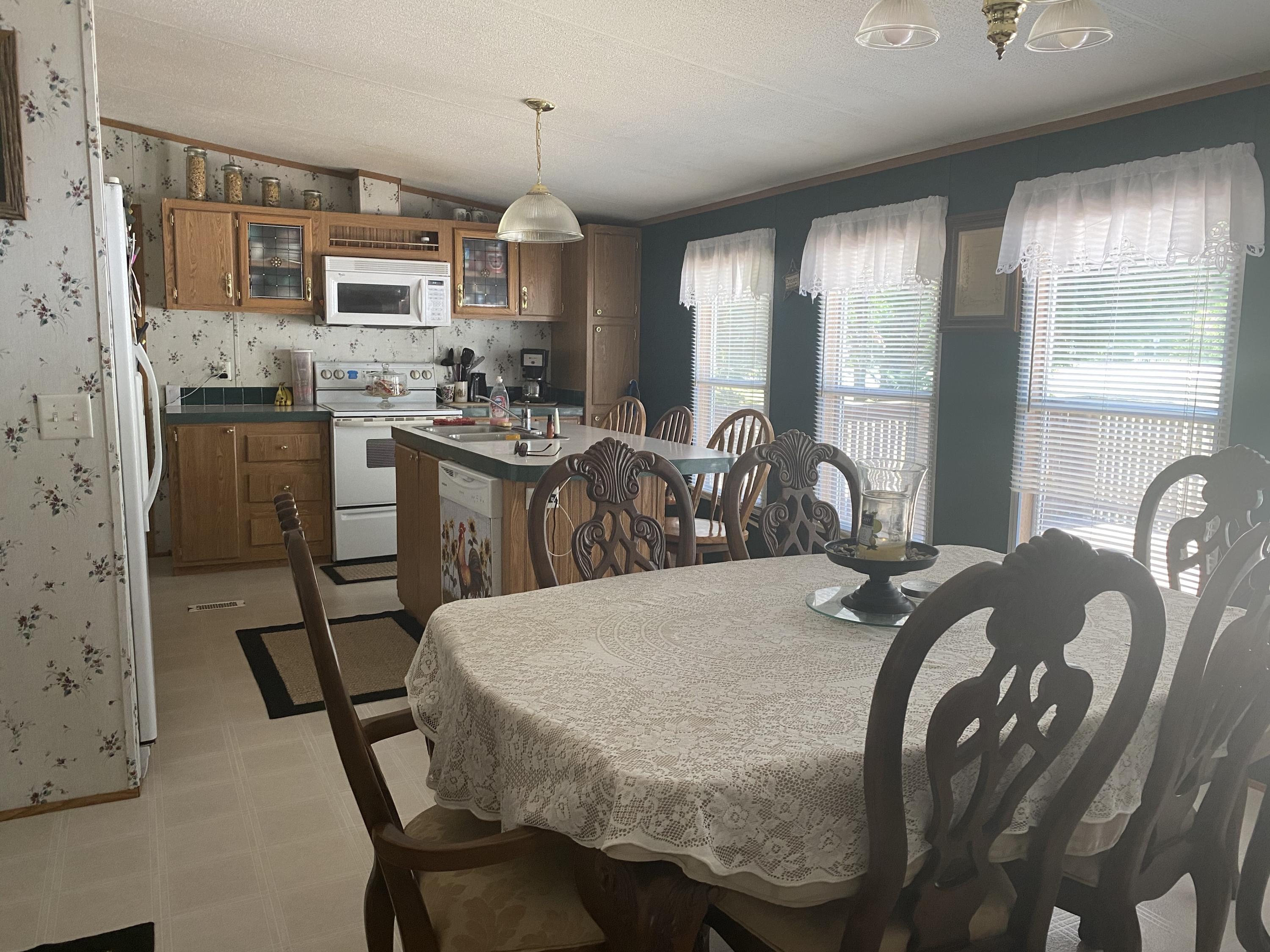 106 Brake Road Elliston, VA 24087 - Photo 3 of 13 a kitchen with stainless steel appliances granite countertop a stove a sink dishwasher a dining table and chairs with wooden floor
