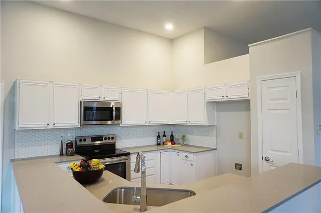 a kitchen with a sink stainless steel appliances and white cabinets