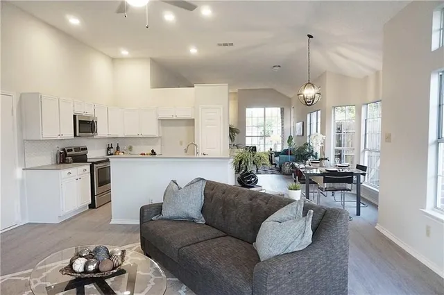 a living room with furniture kitchen area and a chandelier