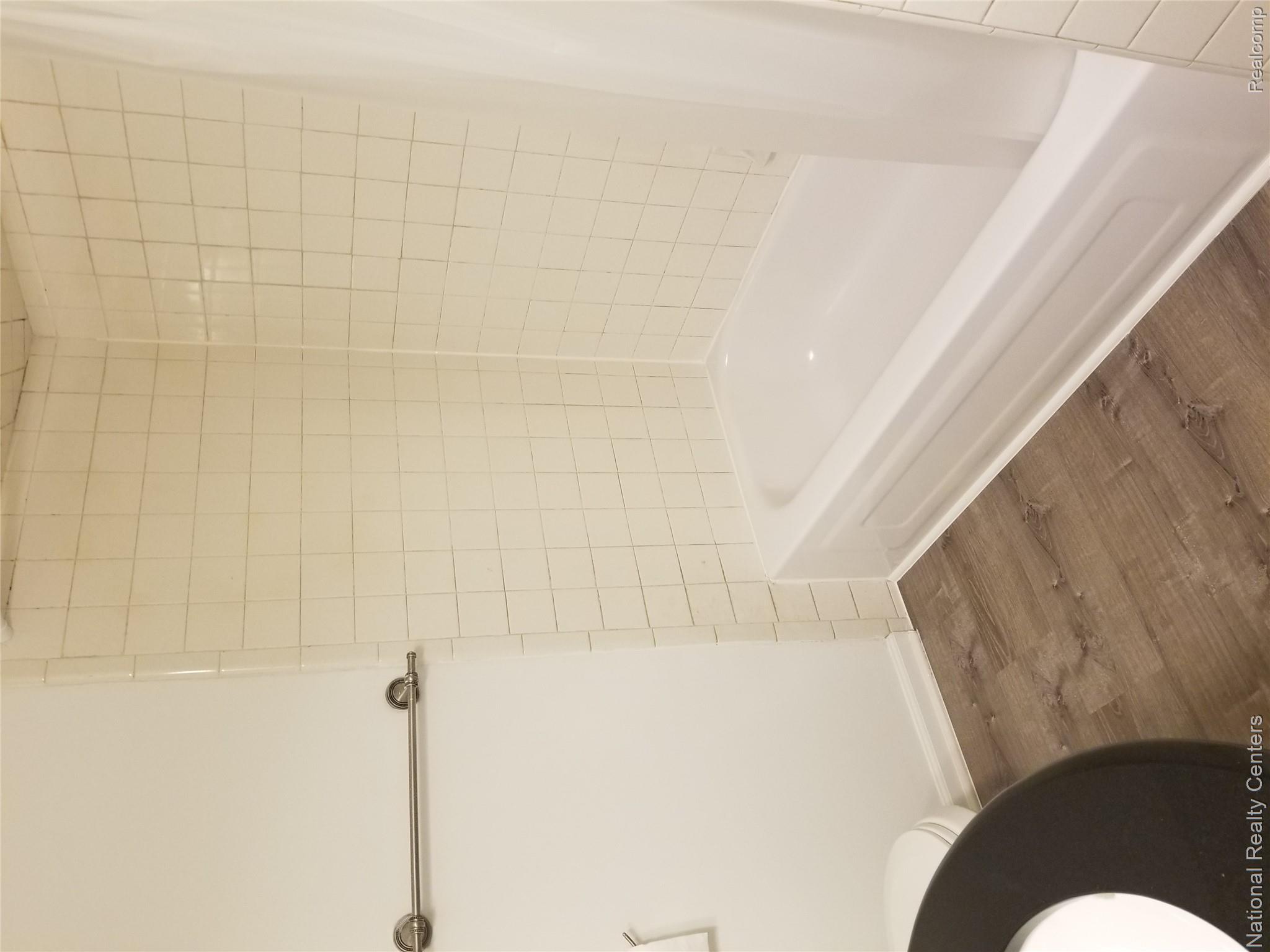 15175 Raphael Terrace Warren, MI 48088 - Photo 20 of 20 Bathroom featuring a white tub, white tiled surround, wood-finish flooring, and a towel bar