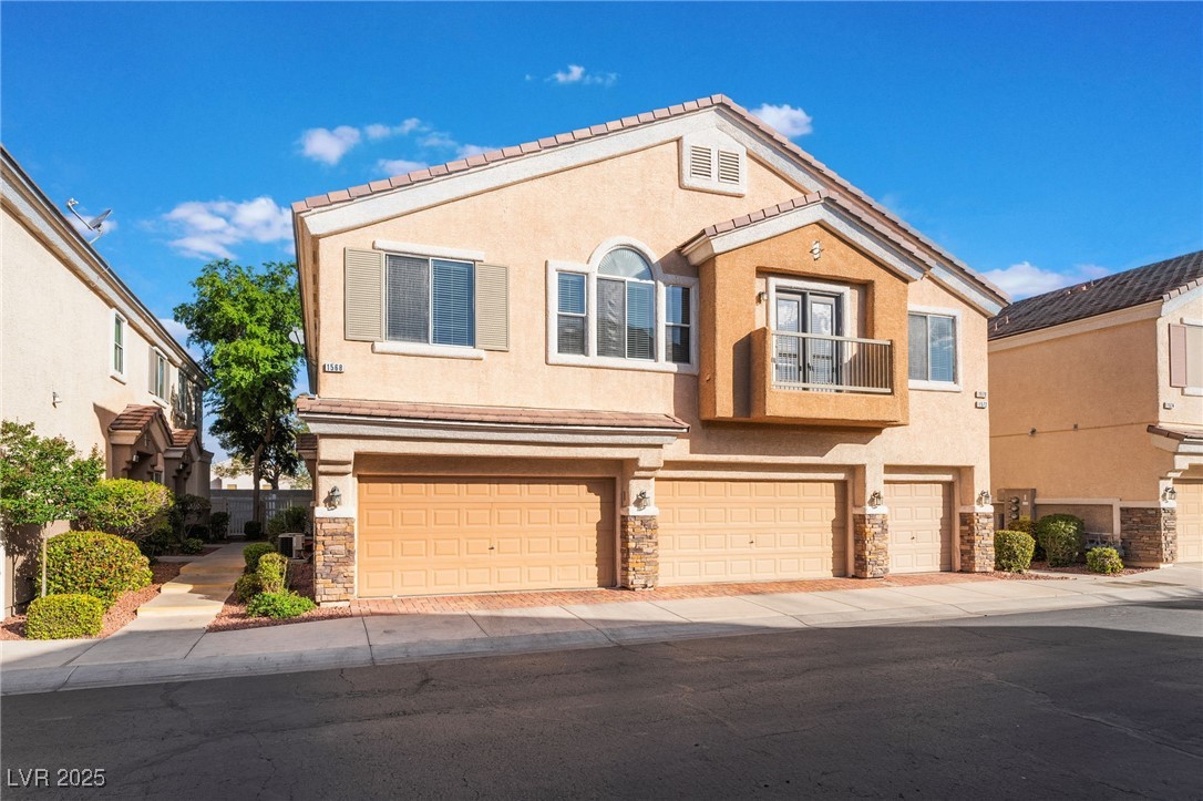 1570 Rusty Ridge Lane Henderson, NV 89002 - Photo 2 of 35 View of front of house featuring stone siding, a garage, a balcony, stucco siding, and driveway