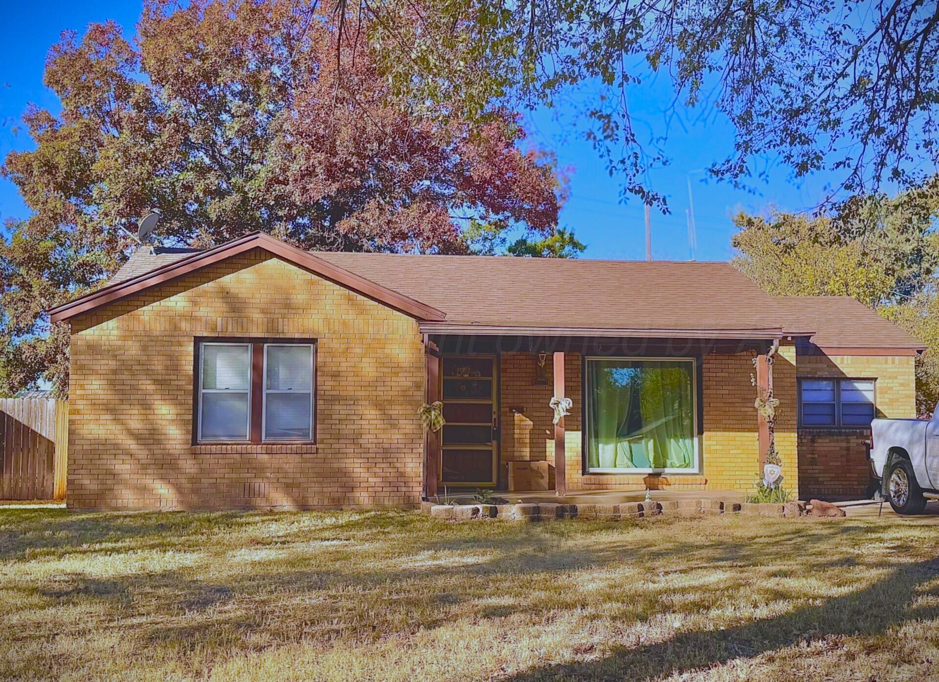 a view of a brick house with large windows and a small yard