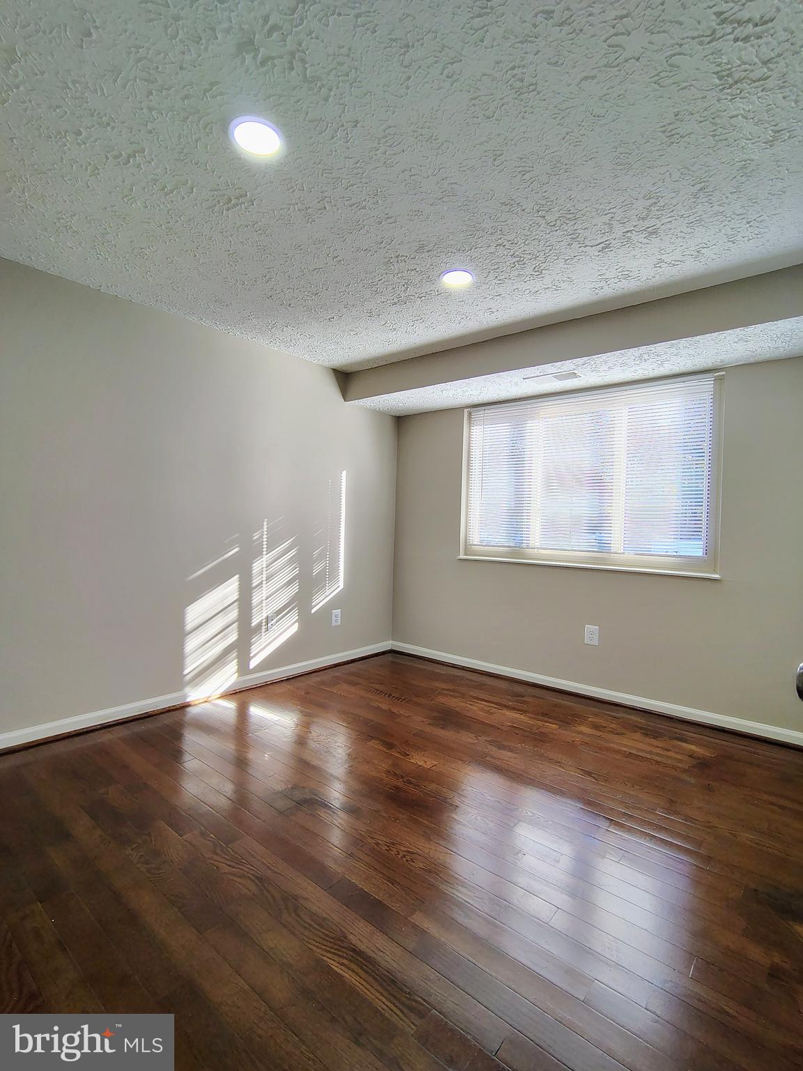 12407 Hickory Tree Way, Unit 524 Germantown, MD 20874 - Photo 14 of 21 a view of an empty room with wooden floor and a window