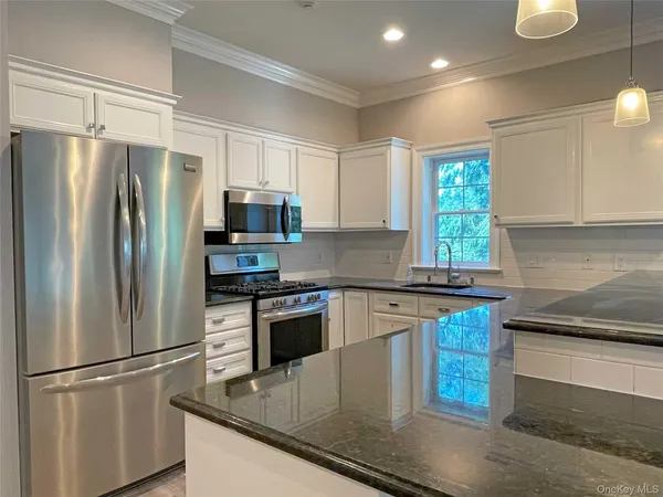 a kitchen with stainless steel appliances granite countertop a refrigerator a stove a sink and a microwave