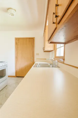 a bedroom with a bed table and two windows