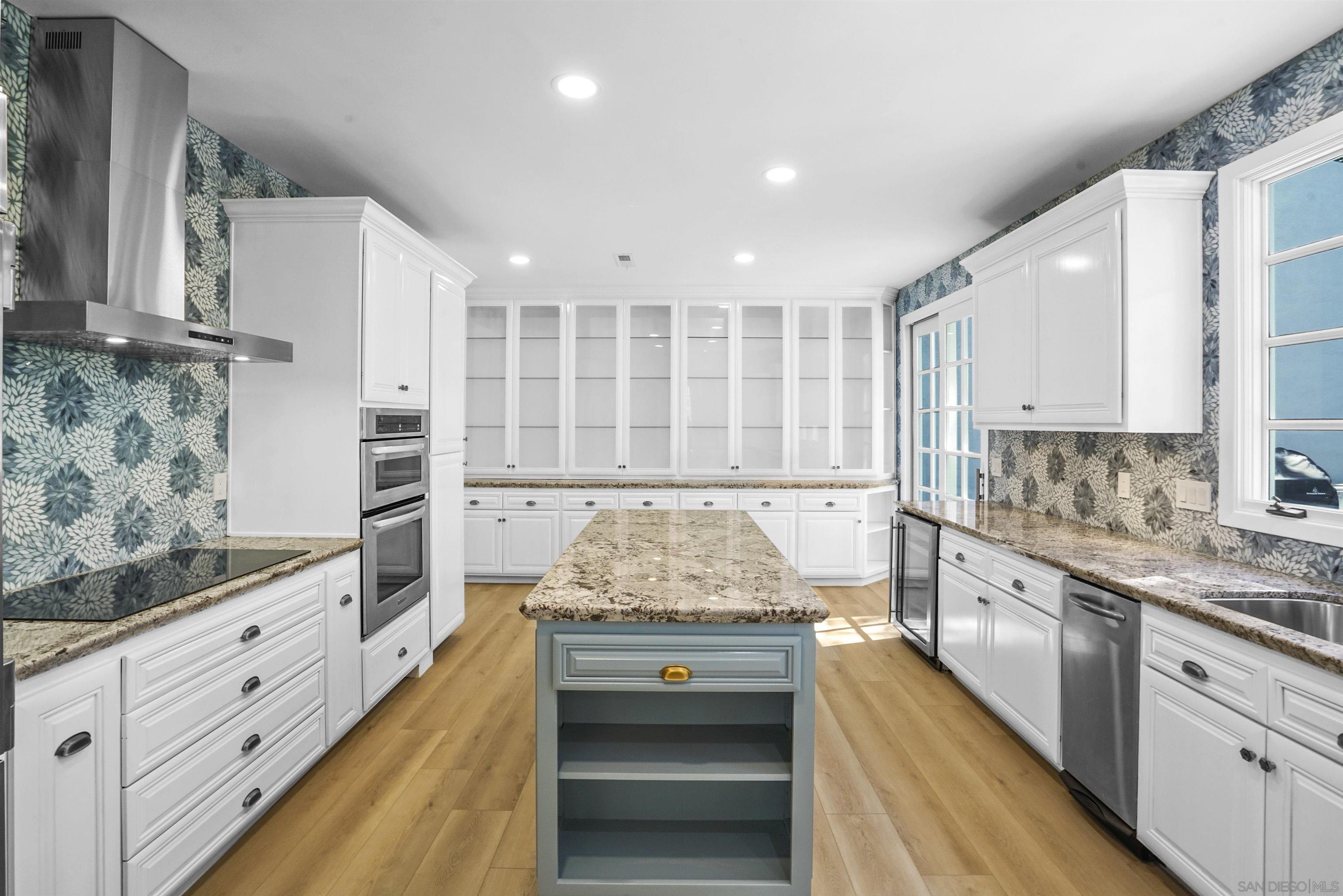 a kitchen with kitchen island granite countertop white cabinets and white stainless steel appliances
