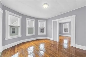 a view of empty room with wooden floor and fan