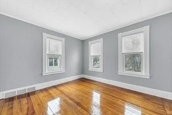 a view of an empty room with a window and wooden floor