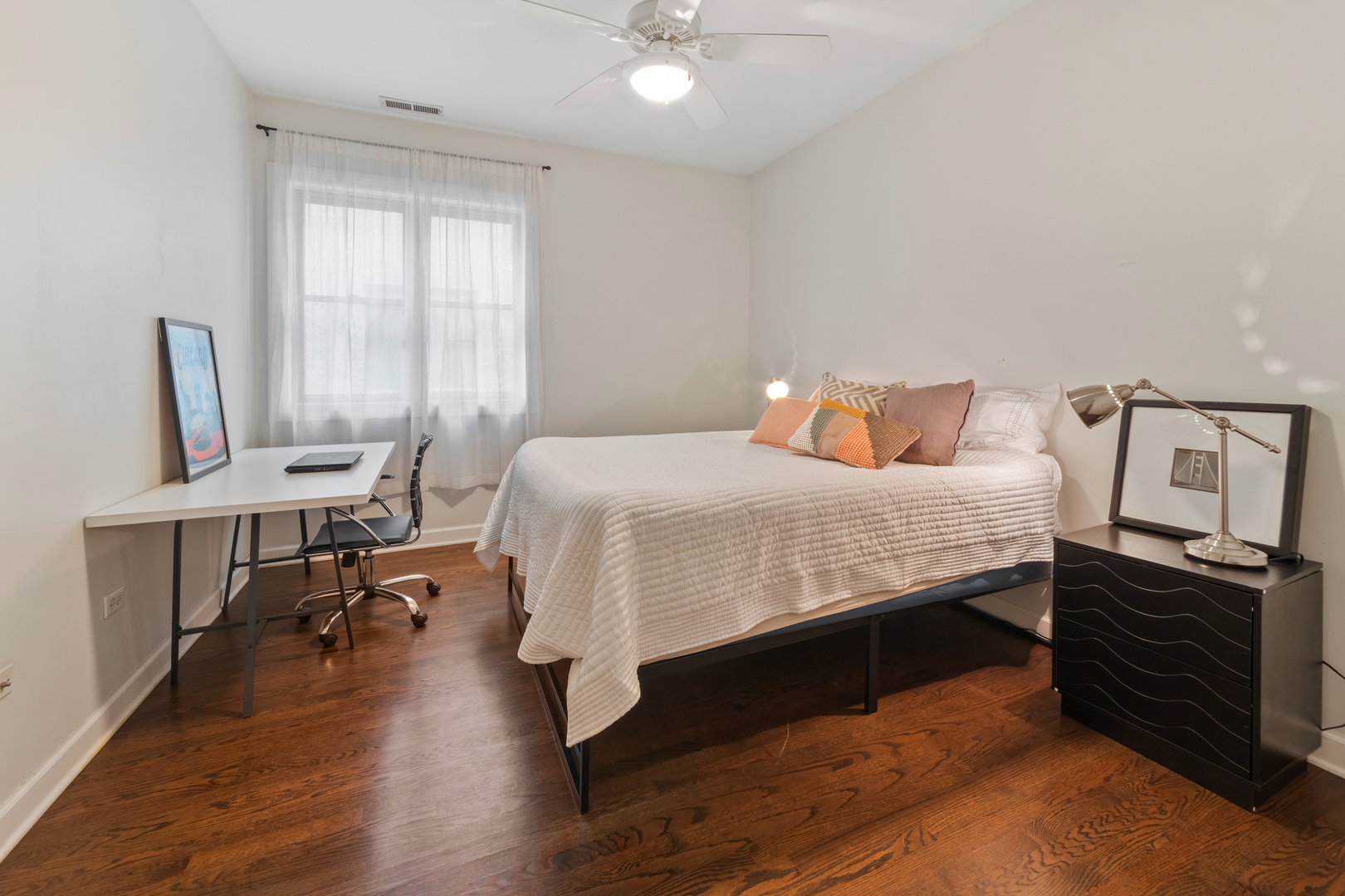 3438 North Ashland Avenue, Unit 2N Chicago, IL 60657 - Photo 20 of 22 a bedroom with a bed a desk and chair with wooden floor