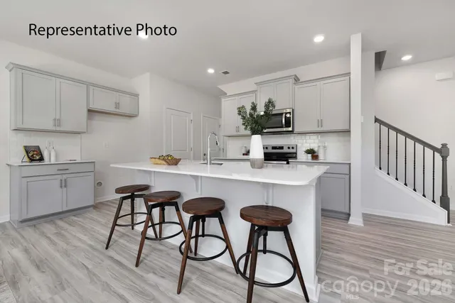 a kitchen with stainless steel appliances a white table chairs and a refrigerator