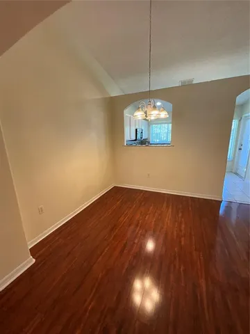 a view of a room with wooden floor chandelier and a ceiling fan