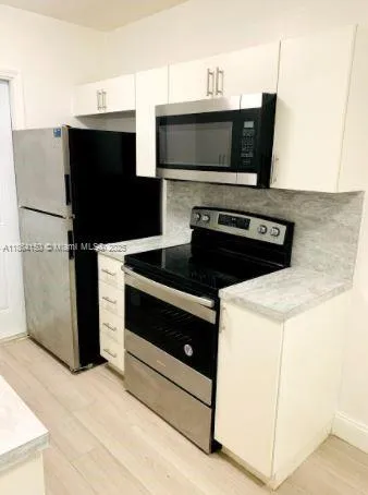 a kitchen with stainless steel appliances a stove microwave and refrigerator