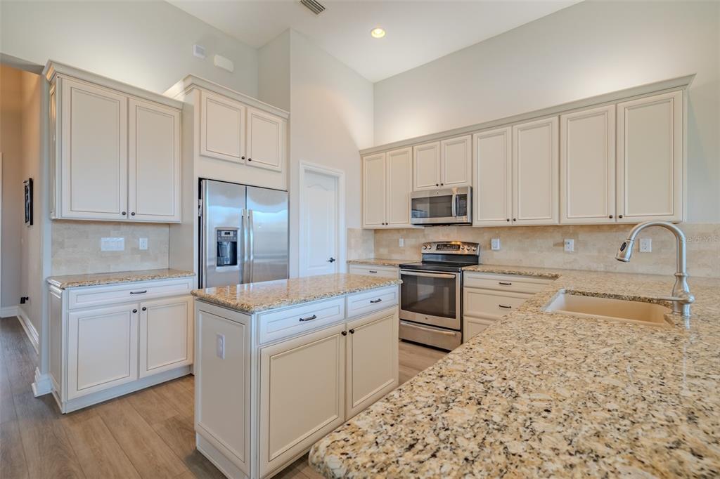 4950 Diamonds Palm Loop Wesley Chapel, FL 33543 - Photo 9 of 65 a kitchen with stainless steel appliances granite countertop a stove a sink and a refrigerator