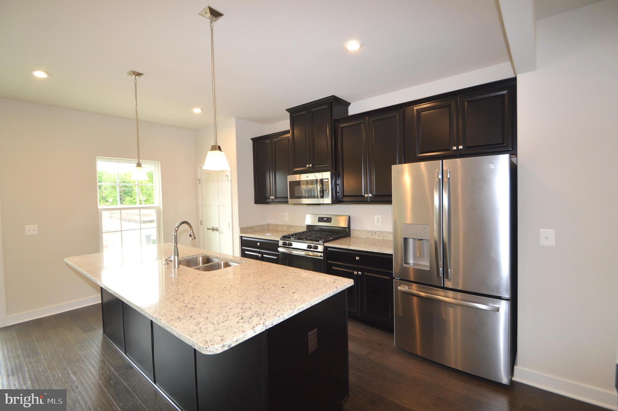 11448 Willow Green Circle Manassas, VA 20109 - Photo 7 of 26 a kitchen with kitchen island a refrigerator a sink a stove a kitchen island with wooden floor and cabinets