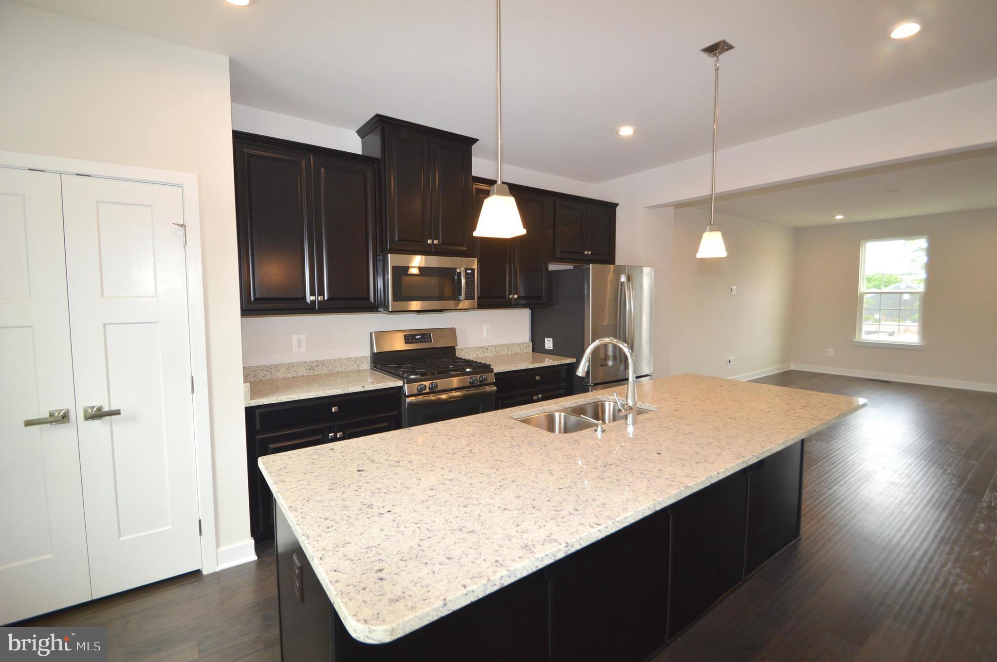 11448 Willow Green Circle Manassas, VA 20109 - Photo 8 of 26 a kitchen with stainless steel appliances a sink dishwasher a refrigerator a microwave oven with white cabinets and wooden floor