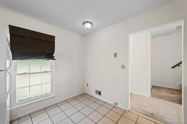 a view of an empty room with window and cabinet