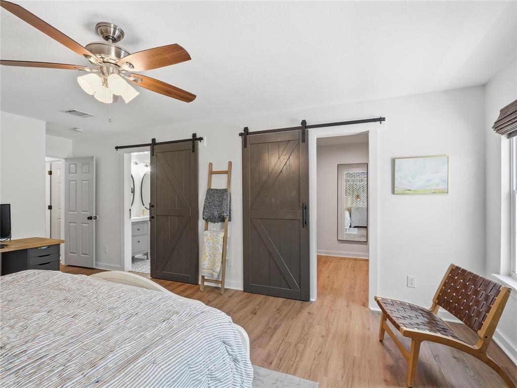 12724 Carpenter Lane Rhome, TX 76078 - Photo 14 of 37 Room featuring wood-finish flooring, two barn-style sliding doors, and a ceiling fan with light fixture