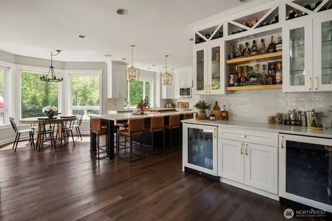 a open kitchen with granite countertop a stove a sink a dining table and chairs with wooden floor