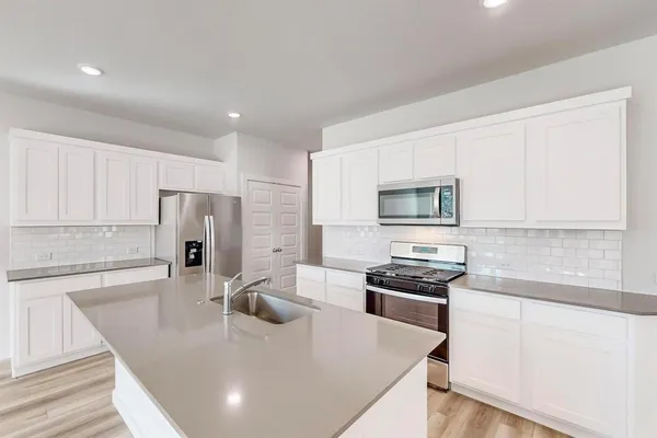 a kitchen with stainless steel appliances granite countertop a sink a stove and a refrigerator