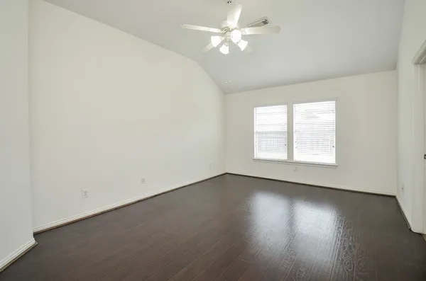 an empty room with wooden floor and windows