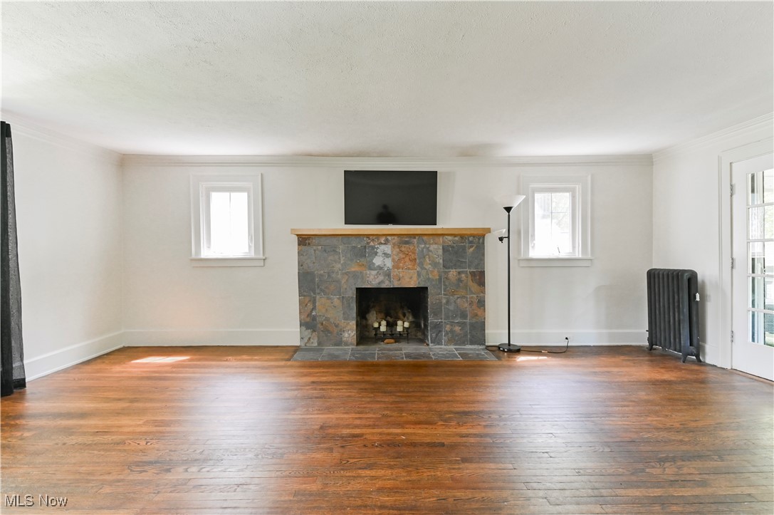 1584 Rydalmount Road Cleveland Heights, OH 44118 - Photo 17 of 36 Unfurnished living room featuring radiator heating unit, crown molding, healthy amount of natural light, and wood flooring