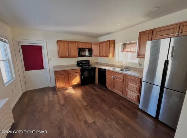 a kitchen with stainless steel appliances granite countertop a refrigerator sink and wooden cabinets