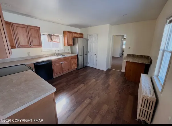 a kitchen with a sink a refrigerator and wooden floor