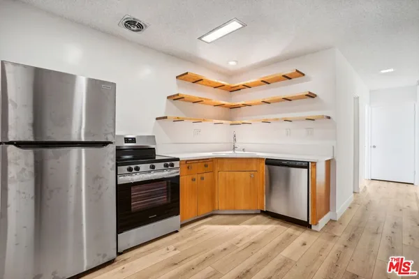 a kitchen with stainless steel appliances granite countertop a refrigerator a sink and a stove