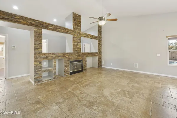 a view of an empty room with wooden floor and a ceiling fan