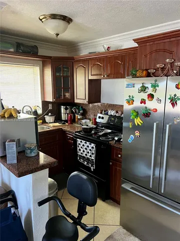 a kitchen with stainless steel appliances granite countertop a refrigerator a sink dishwasher a dining table and chairs with the kitchen view