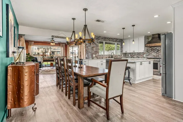 a dining area with furniture a chandelier and wooden floor