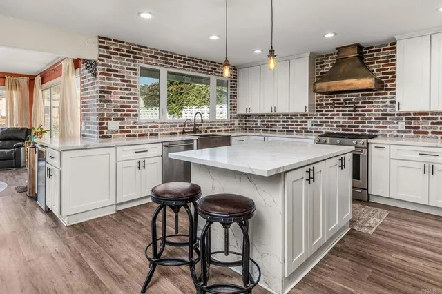 a kitchen with stainless steel appliances granite countertop a sink a stove and a wooden floors