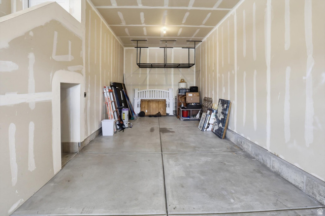 3636 West 910 South Syracuse, UT 84075 - Photo 56 of 70 Spacious garage with unfinished drywall, concrete flooring, and an overhead storage rack