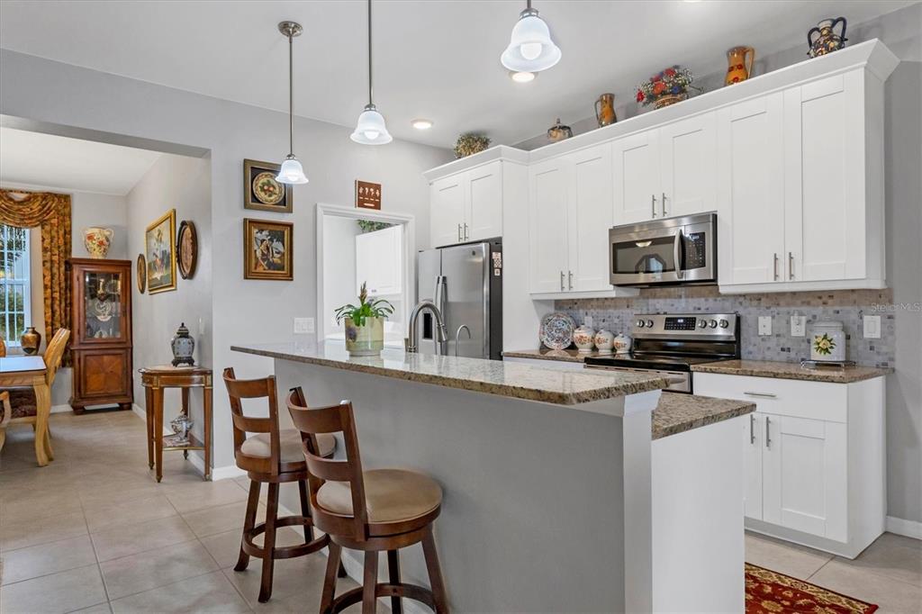 2694 Hopwood Road North Port, FL 34287 - Photo 18 of 56 a kitchen with stainless steel appliances granite countertop a sink a stove a microwave a refrigerator a dining table and chairs with wooden floor