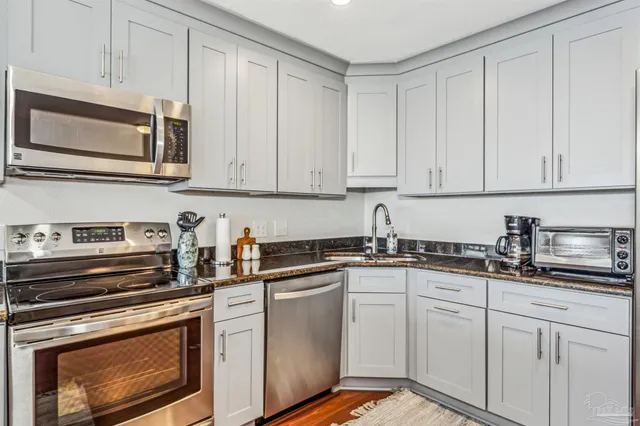 a kitchen with granite countertop white cabinets and stainless steel appliances