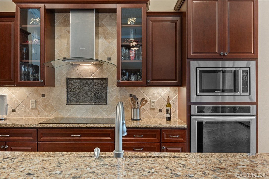 2015 North Rhodes Point Hernando, FL 34442 - Photo 12 of 82 Upgraded finishes throughout the home add to its beauty. The professional Hood Vent, Tile Backsplash, glass front display cabinets, and under cabinet lighting add to the inviting appeal of the kitchen.