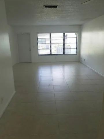 an empty room with a ceiling fan and windows