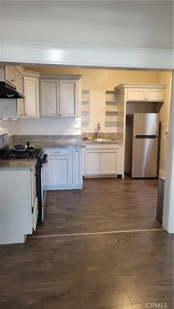 a kitchen with granite countertop a stove a sink and a refrigerator