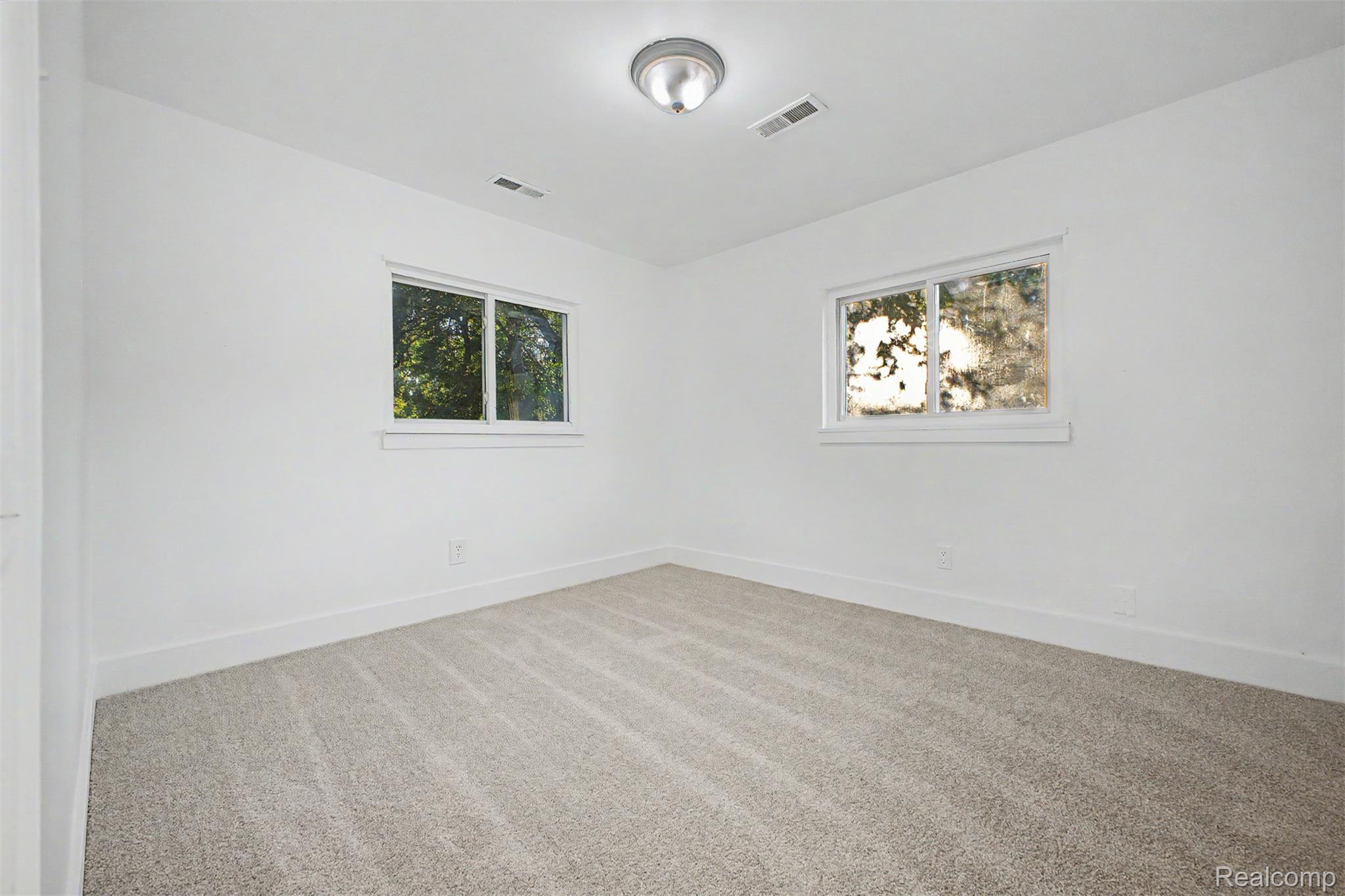 26718 Penn Street Inkster, MI 48141 - Photo 22 of 27 Bright room featuring two windows, neutral wall paint, light-toned carpeting, white baseboards, and a flush-mount ceiling fixture