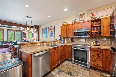 a kitchen with stainless steel appliances granite countertop a stove a sink dishwasher and a refrigerator with wooden cabinets