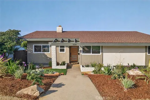 a front view of a house with a yard and potted plants