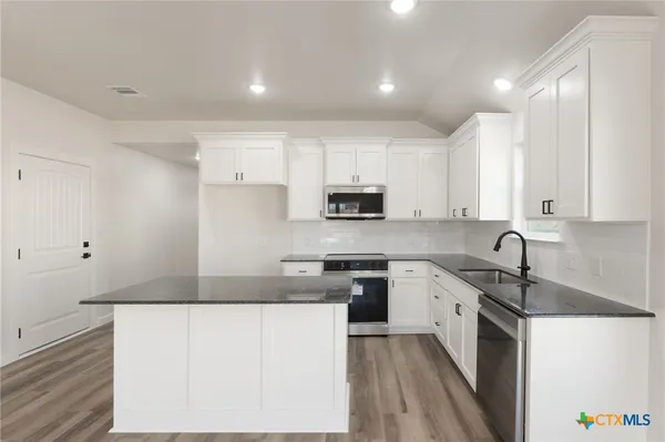 a kitchen with granite countertop a sink stove and refrigerator