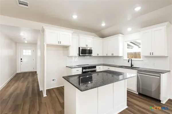 a kitchen with granite countertop white cabinets and white appliances
