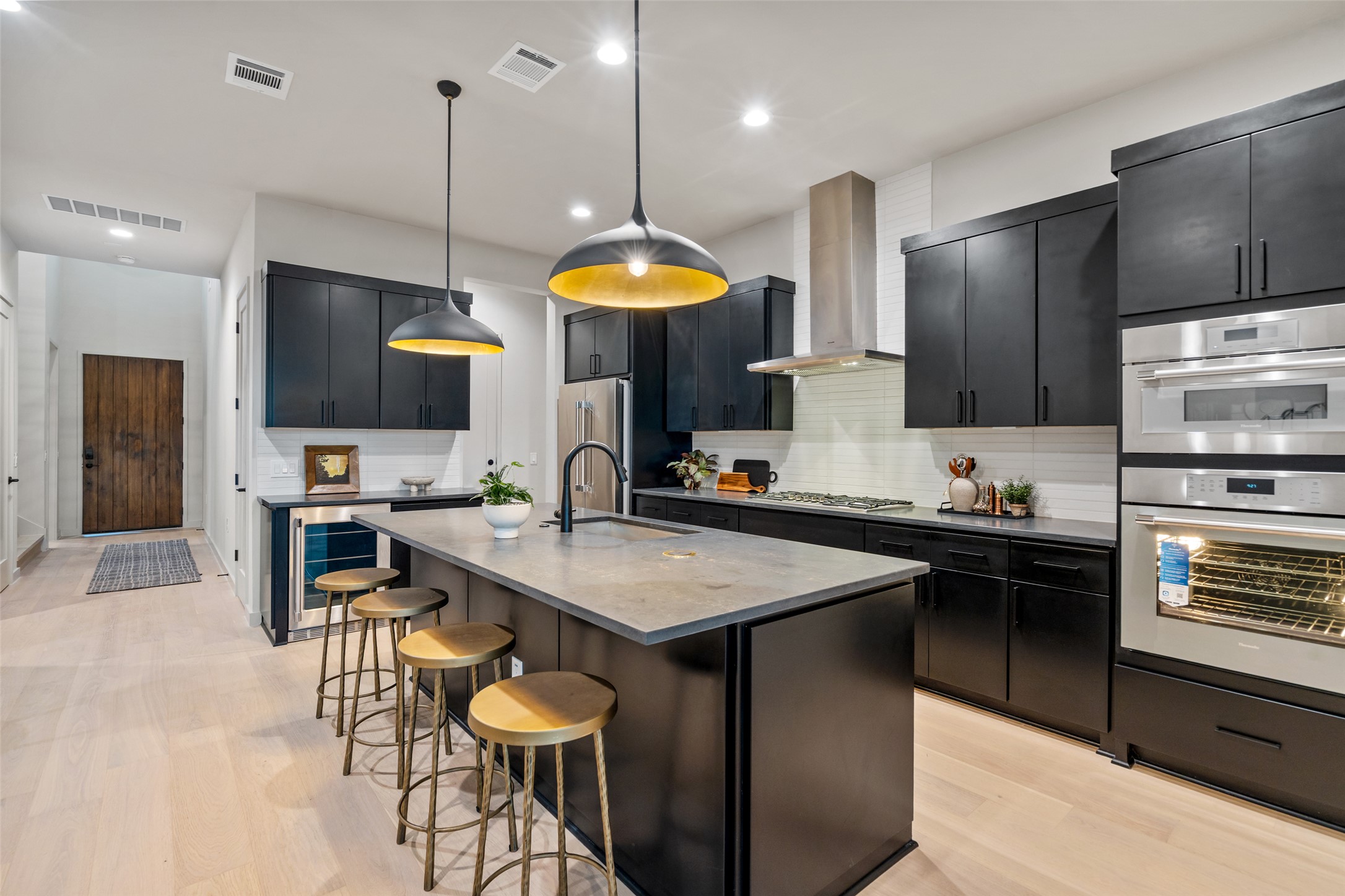 9803 Ribelin Ranch Court, Unit 6 Austin, TX 78750 - Photo 6 of 31 A contemporary chef's kitchen boasts a central island, elegant dark cabinetry, and premium stainless steel appliances.
